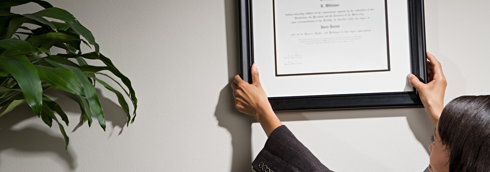 Person hanging a diploma on the wall 